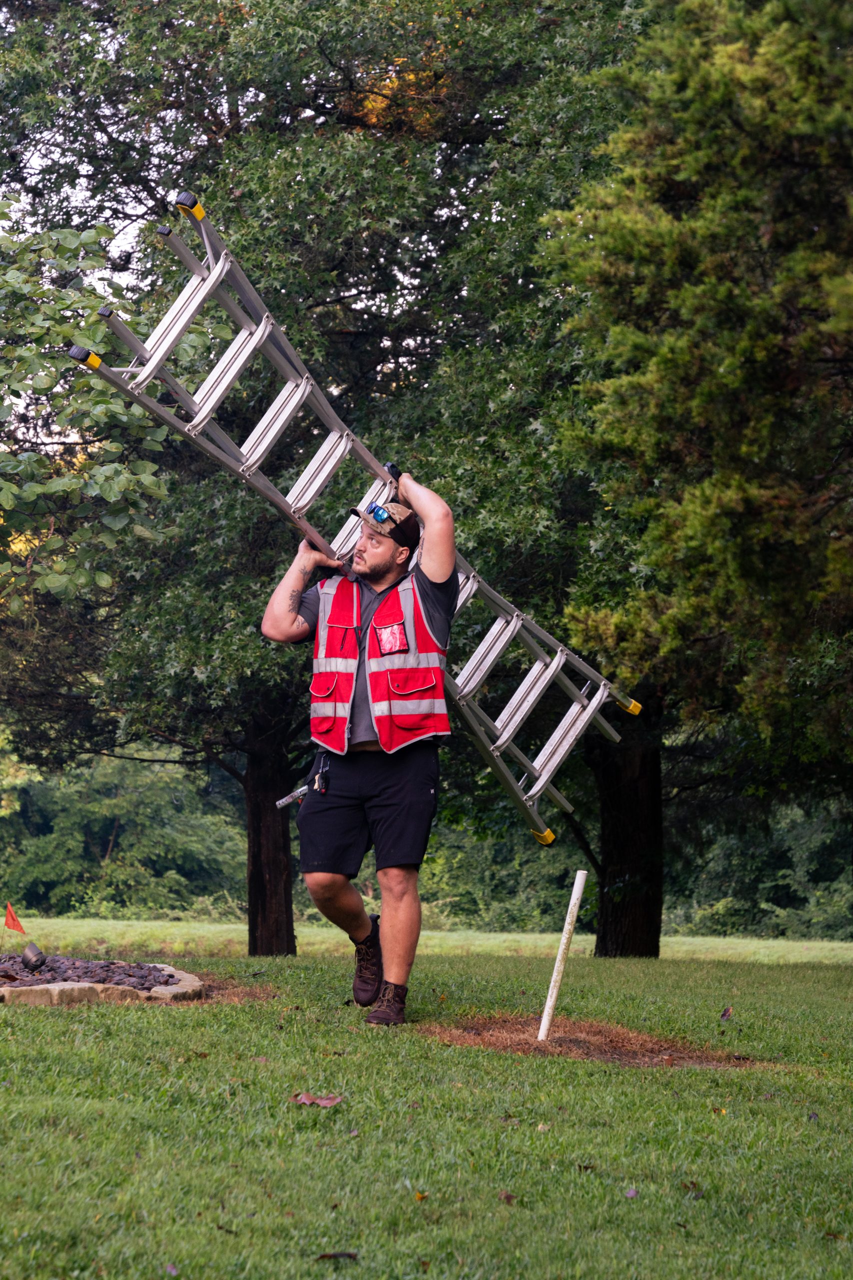 Integrity Roofing & Exteriors worker carrying an extension ladder outdoors